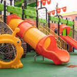 A courtyard of high-rise buildings with a new modern colorful and large playground on a rainy summer day without people. Empty outdoor playground. A place for children's games and sports. Laudo Técnico Brinquedos